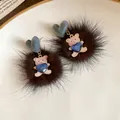 Close-up of fuzzy brown pom-pom earrings featuring a cute pink bear with a blue heart jewel. - 13# Silver Needle Style / Black/Dark Brown