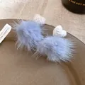 Detailed view of blue faux fur pom-pom earrings featuring white knitted heart accents - Style 19 Short (Silver Post) / White/Blue