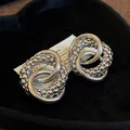 Macro view of silver knotted stud earrings featuring smooth and textured intertwined rings - Round Knot Style (HE18638) / Silver