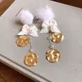 Close-up detail of elegant white fur ball earrings with ribbon bows and hammered gold discs - 35# Silver Needle Style / Gold/White