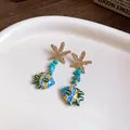 Detailed close-up of starfish and blue glass fish drop earrings with turquoise stone beads - Starfish Lampwork Fish (Steel Post Gold) / Blue