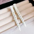 Close-up of two white metal duckbill hair clips on a velvet jewelry tray. - 55# Duckbill Clip - Hollow Round Holes