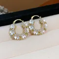 Primo piano di orecchini a cerchio placcati oro 14K con delicati petali bianchi. - Fibbia per orecchie / Placcato Oro 14k / Oro-Bianco