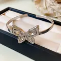 Detailed close-up of a silver open bangle with a sparkling diamond butterfly centerpiece. - Butterfly Open Bangle / Silver
