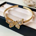 Close-up of golden butterfly cuff bracelet with inlaid crystals on jewelry box - Butterfly Open Bangle / Gold