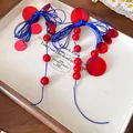 Close-up of red and blue tassel earrings with bow design on a display board - Bow Tassel / Red-Blue