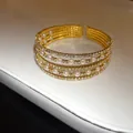 Macro view of a luxurious multi-layer gold open cuff bracelet with rhinestones and pearls. - Quintuple Layer Style / Gold