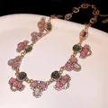 Detailed close-up of a vintage floral necklace featuring pink resin stones and rhinestones. - Brown and Pink