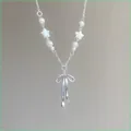 Detailed close-up of a French style bow pendant pearl necklace with white star beads - Necklace / Silver