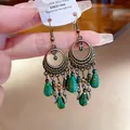 Primo piano di eleganti orecchini etnici a goccia con pietre verdi e cerchi in bronzo. - Stile a Gancio / Verde