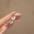 Gros plan de boucles d'oreilles fleurs roses tenues sur un doigt pour les détails - Bouquet de fleurs / Rose