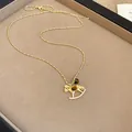 Détail d'un pendentif cheval à bascule doré orné d'une pierre œil de tigre et de cristaux. - Or