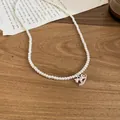 Détail élégant d'un collier de perles avec pendentif cheval à bascule rose - Blanc-Rose