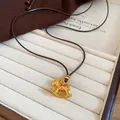 Vue macro d'un pendentif cheval à bascule doré de luxe avec accents de diamants sur cordon brun - Or
