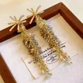 Nahaufnahme von Vintage-Kristall-Quastenohrringen mit Zirkonia-Blumensteckern. - Blumen-Quasten-Stil / Gold