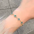 Detail of elegant gold bracelet with blue zircon diamond-shaped floral links on wrist. - Gold-Blue