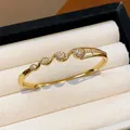 Gros plan d'un jonc doré 18k avec motifs floraux en zircon dans un écrin à bijoux beige - Style 11 (Or)