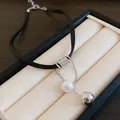 Gros plan détaillé du pendentif perle et perle argentée sur un collier en cuir noir - Collier ras-du-cou / Noir Blanc Argent