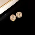 Primo piano di eleganti orecchini a lobo tondi con cristalli scintillanti e finitura oro. - Stud orecchini / Perno in argento-Bianco