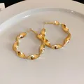 Detailed view of elegant golden twisted spiral hoop earrings with metallic finish - Gold