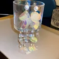 Détail de boucles d'oreilles à pampilles avec paillettes irisées et perles sur un verre - Style Perle Paillettes Colorées / Coloré
