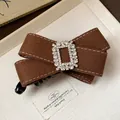 Close-up detail of brown fabric bow hair clip with elegant sparkling rhinestone buckle. - Twist Clip / Brown