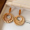 Detail of bohemian woven earrings with wooden beads and round rattan drop design. - Hook Style / Brown