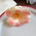 Primo piano di una molletta per capelli a fiore in schiuma sfumata pesca su un piatto - Fermagli per capelli a becco d'anatra / Rosa-Bianco