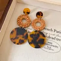 Close-up of vintage bohemian rattan woven earrings with tortoiseshell resin discs - Silver Earring Post Style / Brown