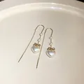 Detaillierte Nahaufnahme eleganter Perlenherz-Ohrhänger mit goldenem Schleifen-Design - Schleife Herz Perle Stil / Gold