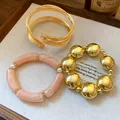 Close-up detail of metal, acrylic, and pearl stretch bracelet set on a wooden tray - 3-Piece Bracelet Set / Gold-Pink