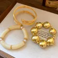 Detailed view of elegant gold beaded, acrylic, and multi-wire bracelet set in tray - 3-Piece Bracelet Set / Gold-Khaki