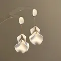Dettaglio di eleganti orecchini con petali di fiori in acrilico bianco e oro - Bottoni con nappa / Oro-Bianco