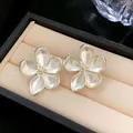 Primer plano de elegantes pendientes de flor de cinco pétalos con un acabado perlado - Plateado