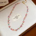Vue détaillée d'un collier de perles en verre coloré sur un plateau texturé blanc - Collier perlé ras du cou / 46+9cm / Rose