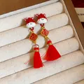 Primo piano di eleganti orecchini a cavallo in smalto rosso con ciondolo 'Fu' e nappe - Orecchini Cavallo con Carattere Fu a Rombo / Rosso