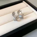 Macro view of minimalist silver twisted braid hoop earrings in a cream jewelry box - Ear Buckle / Silver