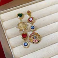 Detailansicht luxuriöser asymmetrischer Ohrringe mit bösem Blick und Hamsa-Anhängern - Silber-Ohrstecker - Gold - Bunt