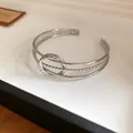 Vista dettagliata di un bracciale rigido aperto minimalista in argento intrecciato - Stile Torsione ad Anello / Argento