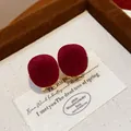 Macro view showing the soft red flocked texture of these elegant gold-toned geometric stud earrings - Round Flocked Gold Style (HE30499) / Red