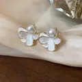 Dettaglio ravvicinato di eleganti orecchini a fiore con perle e bordi dorati su seta - Orecchini a clip / Oro Bianco