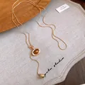 Macro detail of a vintage oval resin pendant on a golden snake chain necklace - Oval Design / Gold