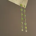 Close-up of elegant long drop earrings with translucent green crystals and gold chains - Silver Earring Post Style / Gold Green Combination