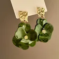 Detail view of vintage green flower drop earrings featuring a hammered gold metal base - Silver Earring Post Style / Green