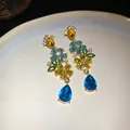 Vista detallada de elegantes pendientes de flores de cristal con gotas azules colgantes - Dorado-Azul-Amarillo