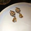 Primer plano de pendientes de flor elegantes con gotas de cristal color ámbar - Negro de Humo-Café