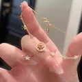 Vue détaillée d'un élégant bracelet doré orné de charmes boussole et étoile en zircon - Or