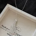 Detalle de un collar con colgante de borla plateada en una bandeja beige texturizada - Plata (7#)