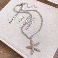 Detalle de un colgante de estrella de mar plateada con textura sobre un libro vintage - Plateado Estrella de Mar (13#)