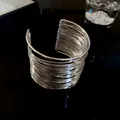 Macro detail of a silver-toned multi-layer wire open cuff bracelet on dark surface - Bangle / Silver